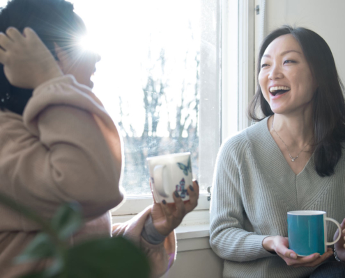 two ladies holding mugs and chatting happily to each other.